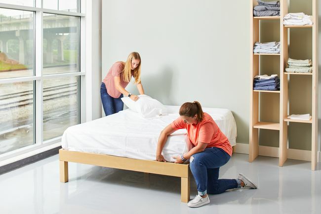 deux femmes faisant un lit avec des draps blancs